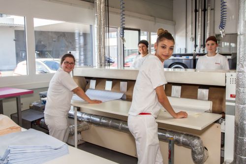 Lehrlinge aus der Textilreinigung beim Arbeiten an der Mangel © Wien Work
